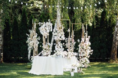 Düğün için. Ziyafet. Sandalyeler ve yuvarlak masa misafirler için çatal bıçak takımı, yeşillik çiçekleri ve çanak çömlek ile servis ediliyor ve beyaz bir masa örtüsüyle kaplanıyor. zeytin rengi