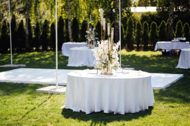 Düğün için. Ziyafet. Sandalyeler ve yuvarlak masa misafirler için çatal bıçak takımı, yeşillik çiçekleri ve çanak çömlek ile servis ediliyor ve beyaz bir masa örtüsüyle kaplanıyor. zeytin rengi