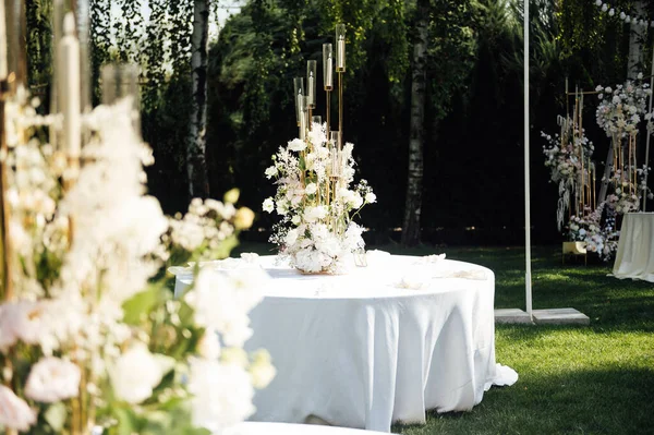 Wedding. Banquet. The chairs and round table for guests, served with cutlery, greenery flowers and crockery and covered with a white tablecloth. olive color