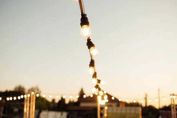 Decorative lighting lamps at a wedding party. Evening sunset.