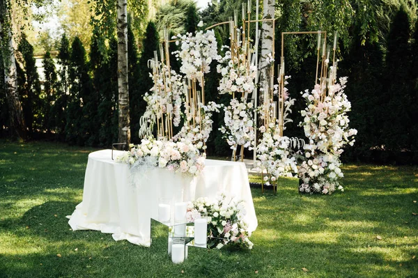 新婚旅行のためのウェディングテーブル設定 白い皿およびナプキン 緑および花およびろうそく 屋外で飾られるお祝いのテーブル ロイヤリティフリーのストック写真