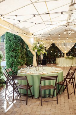 Açık hava düğün restoranı. Taze çiçekler ve özel yemeklerle süslenmiş. Çiçekli ve lambalı konuklar için masalar.