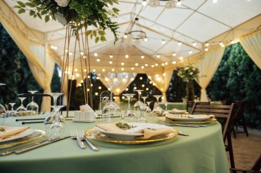 Açık hava düğün restoranı. Taze çiçekler ve özel yemeklerle süslenmiş. Çiçekli ve lambalı konuklar için masalar.