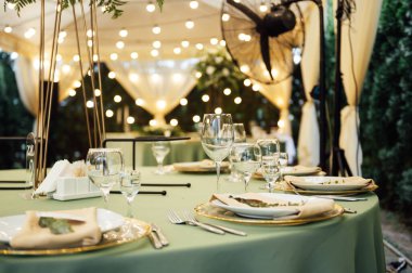 Açık hava düğün restoranı. Taze çiçekler ve özel yemeklerle süslenmiş. Çiçekli ve lambalı konuklar için masalar.