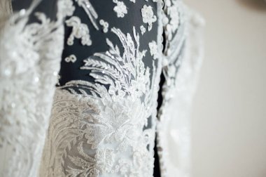 Beyaz arka planda işlemeli ve dantelli modern bir gelinlik. Efendinin elinden yapılmış..