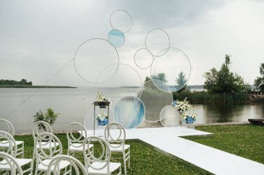 Nehir sahilinde düğün için açık havada bir yer. Yuvarlak kemerin büyük bir kurulumu. Düğün ayarları