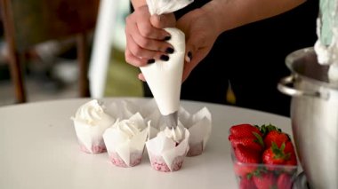 Aşçı kız pastaları süslemek için kremayı mikserden kalıba koyuyor..