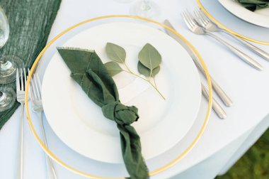 Açık hava düğün ziyafeti. Bir düğün partisinde masanın yakın çerçevesi. Masada tabaklar, fincanlar ve diğer eşyalar var.