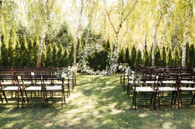 Beyaz çiçekler ve açık hava yeşilliği ile süslenmiş daire şeklinde düğün kemeri. Düğün hazırlığı. Çiçek bileşimi