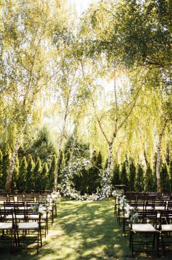 Beyaz çiçekler ve açık hava yeşilliği ile süslenmiş daire şeklinde düğün kemeri. Düğün hazırlığı. Çiçek bileşimi