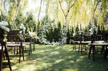 Beyaz çiçekler ve açık hava yeşilliği ile süslenmiş daire şeklinde düğün kemeri. Düğün hazırlığı. Çiçek bileşimi