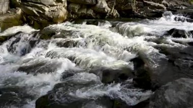 Vahşi dağ nehri taş kayaların arasından akıyor. Karpatlar 'da bol miktarda temiz dere var. Nehrin kenarına soğuk su sıçrıyor. Ulusal parktaki kayalardan küçük bir taşma. Su arkaplanı kavramı
