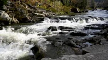 Vahşi dağ nehri taş kayaların arasından akıyor. Karpatlar 'da bol miktarda temiz dere var. Nehrin kenarına soğuk su sıçrıyor. Ulusal parktaki kayalardan küçük bir taşma. Su arkaplanı kavramı