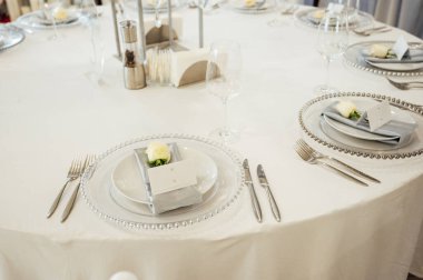 Bir restorandaki düğün yemeğinde konuklar için sofrada çatal bıçak ve tabaklar var..