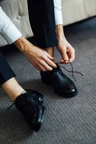 A man ties his black shoes. Close-up view