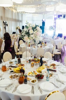 Düğün için. Ziyafet. Sandalyeler ve yuvarlak masa misafirler için çatal bıçak takımı, yeşillik çiçekleri ve çanak çömlek ile servis ediliyor ve beyaz bir masa örtüsüyle kaplanıyor. zeytin rengi