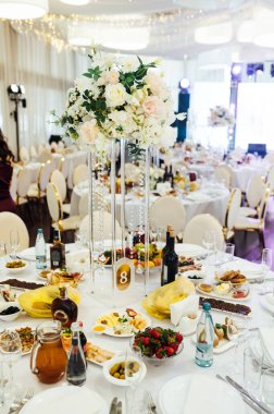 Düğün için. Ziyafet. Sandalyeler ve yuvarlak masa misafirler için çatal bıçak takımı, yeşillik çiçekleri ve çanak çömlek ile servis ediliyor ve beyaz bir masa örtüsüyle kaplanıyor. zeytin rengi