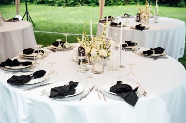 Açık hava düğün ziyafeti. Masa beyaz tabaklar ve şarap için özel bardaklarla süslenmiştir..