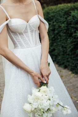 Beyaz elbiseli bir kız elinde bir düğün buketi tutuyor..