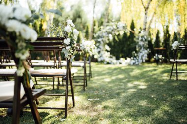 Açık hava düğün töreni için çiçeklerle süslenmiş ahşap sandalyeler..