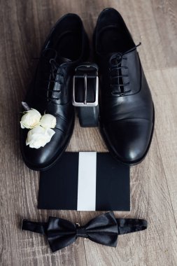 Erkek damatlar hazır. Koyu renk ayakkabı ve kemer. Yakınlarda bir davet mektubu var..