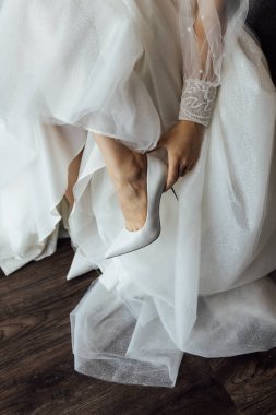 Uzun elbiseli güzel kız sandaletlerini düzeltiyor. Düğün günü.