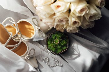 Gelinler düğün aksesuarları buket şeklinde, altın yüzükler ve ayakkabılar. Güzel parlak ayakkabılar ve düğün için bir buket