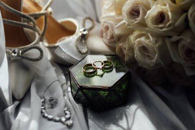 Gelinler düğün aksesuarları buket şeklinde, altın yüzükler ve ayakkabılar. Güzel parlak ayakkabılar ve düğün için bir buket