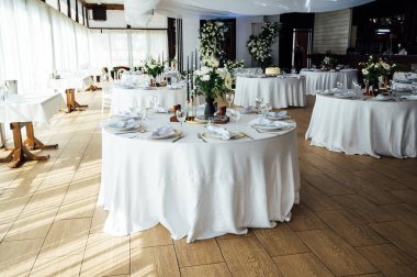 Lüks restoran. Lüks içecekler, beyaz masalar, misafirler için servis tabakları ve bardaklar..