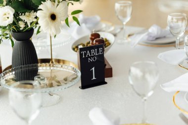 Lüks restoran. Lüks içecekler, beyaz masalar, misafirler için servis tabakları ve bardaklar..