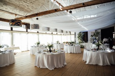 Lüks restoran. Lüks içecekler, beyaz masalar, misafirler için servis tabakları ve bardaklar..