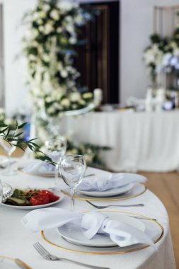 Lüks restoran. Lüks içecekler, beyaz masalar, misafirler için servis tabakları ve bardaklar..