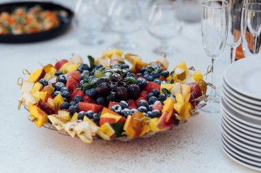 Düğün partisi. Sebze ve meyveli büfe masası. Etkinlikten önce açık büfede konuklar için geniş bir yiyecek seçimi ve çeşitli atıştırmalıklar.