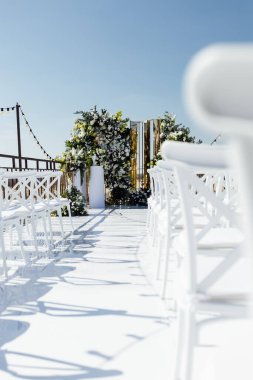 Çiçeklerle süslenmiş bir düğün kemeri, bir podyumda duruyor, açık havada duruyor, nehrin zeminine karşı yapılacak tören için. Fotoğraf, tatil tasarımı konsepti.