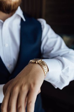 Şık Hazırlık: takım elbiseli şık bir adam ve bileğinde klasik altın bir saat var. Profesyonel dakiklik, iş ahlakı. Damatların düğününe hazırlanıyorum..