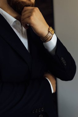 Şık Hazırlık: takım elbiseli şık bir adam ve bileğinde klasik altın bir saat var. Profesyonel dakiklik, iş ahlakı. Damatların düğününe hazırlanıyorum..