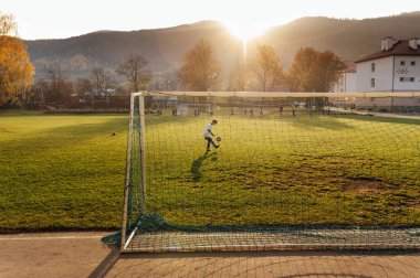 Futbol sahasında poz veren beyaz üniformalı genç bir futbolcu. Okul spor kulübü. Genç oyuncu için alıştırma.