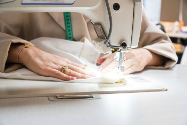 Kadın kendi elbiselerini dikiyor.
