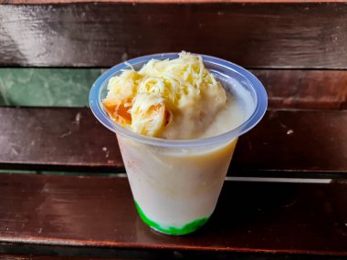 Durian Cendol Buzlu İçeceği. Üstünde rendelenmiş peynir ve ekmek dilimleri var.