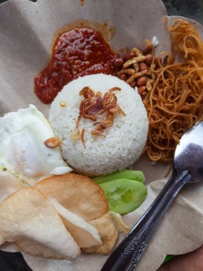 Geleneksel Endonezya kahvaltı tabağı. İçinde Nasi Uduk (pilav), sambal, çıtır fıstık, kızarmış erişte ve kraker ile servis edilen salatalık dilimleri var. Endonezya sokak yemekleri