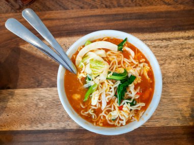 Tahta bir masada servis edilen taze sebzeli Endonezya usulü baharatlı şehriye çorbasının üst görüntüsü. Yemek blogları, yemek menüleri ve kültürel mutfak vitrinleri için mükemmel.