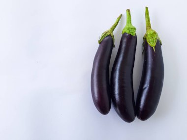 Temiz beyaz arka planda izole edilmiş üç taze mor patlıcanın üst görüntüsü. Yemek blogları, yemek tarifi kitapları, sebze rehberleri ve sağlıklı yemek kavramları için ideal..
