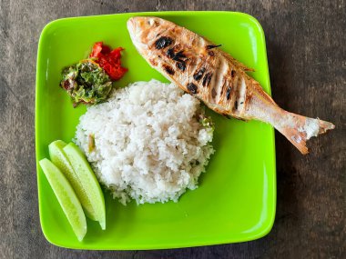 Geleneksel Lauak Sambam tabağı Padang Pariaman, Batı Sumatra, Endonezya 'dan, ızgara balık, buğulanmış pirinç, sambal ve yeşil tabakta taze salatalık