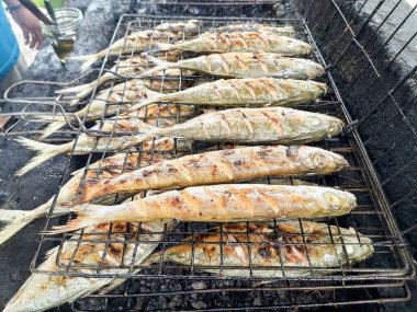 Close-up of gurigak fish being grilled on a charcoal grill, prepared in the traditional Pariaman style called sambam or ikan bakar in Indonesian. Freshly cooked seafood clipart