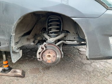 Lastik değiştirme ameliyatı olan bir araba. Tekerlek sökülmüş, süspansiyon sistemi, fren diski ve bileşenleri ortaya çıkmış. Otomotiv ve onarım için mükemmel