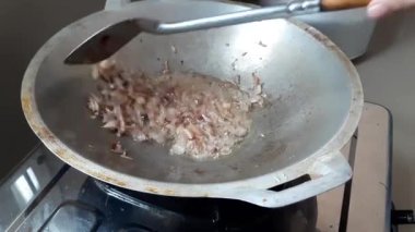 Bir tavada paslanmaz çelikten bir spatulayla kızgın yağda sotelenen arpacık soğanlarının yakın çekimi. Yemek pişirmek ya da yemek pişirmek için mükemmel.