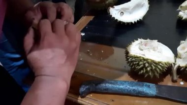 Dikenli bir Durian meyvesini bıçakla açan bir adama yaklaş. Olgun durian ve güçlü bir aroma. Tropik meyve