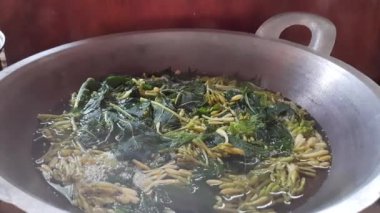 Geleneksel Endonezya tavasında taze haşlanmış papaya yaprakları ve çiçekler. Yerel aşçılık gelenekleri ve sağlıklı malzemelerin sergilendiği klasik bir yemek.