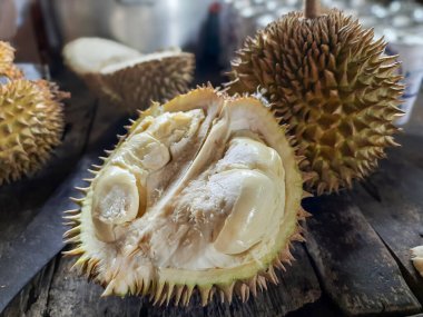 Erimiş bir Durian meyvesinin yakın çekimi kremsi, sarı etini ortaya çıkarmak için açıldı. Kırsal ahşap bir masada. Güneydoğu Asya 'dan tropik meyve