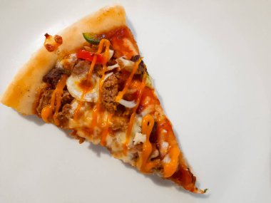 Beyaz bir tabakta servis edilen et, sebze, peynir ve sosla kaplı tek bir dilim pizzayı yakın çekim yapın. Lezzetli fast food konsepti